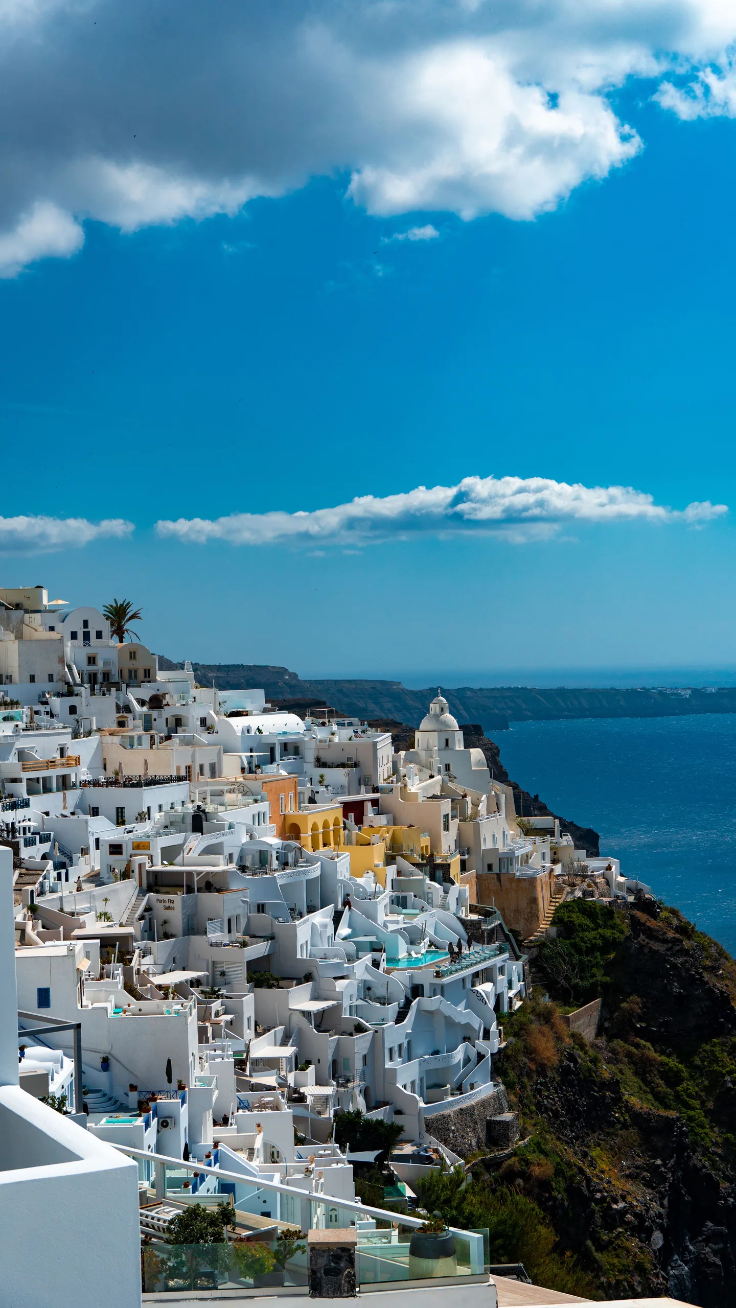 Beautiful view of Fira in Santorini showcasing iconic white buildings against a deep blue sea under a clear sunny sky.