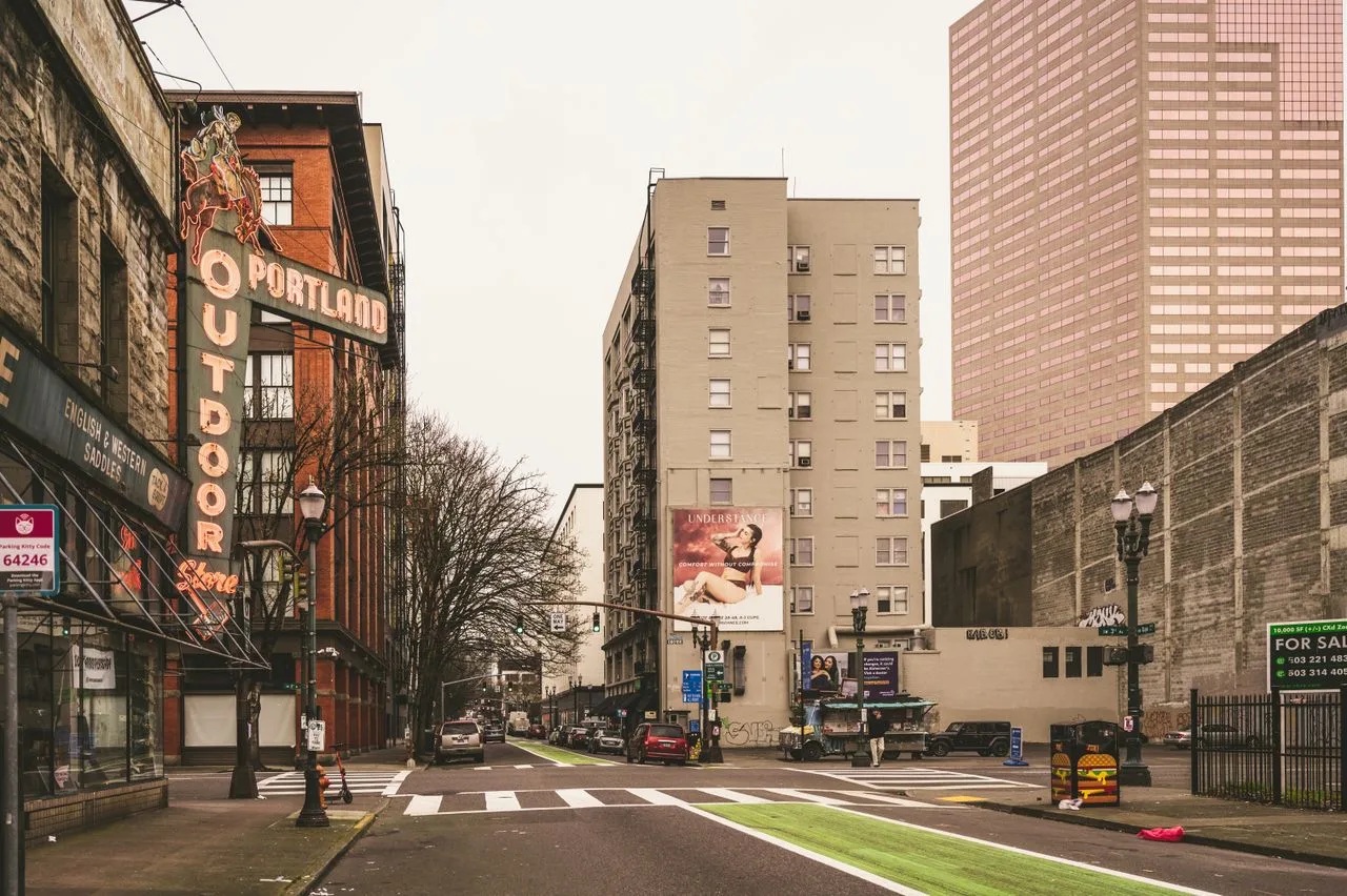 Urban street scene in downtown Portland featuring historic neon sign and modern architecture.