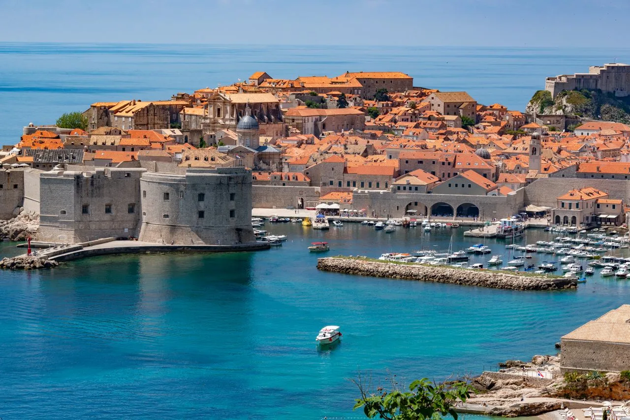 Stunning aerial view of Dubrovnik's historic fortress and marina with vibrant blue waters.
