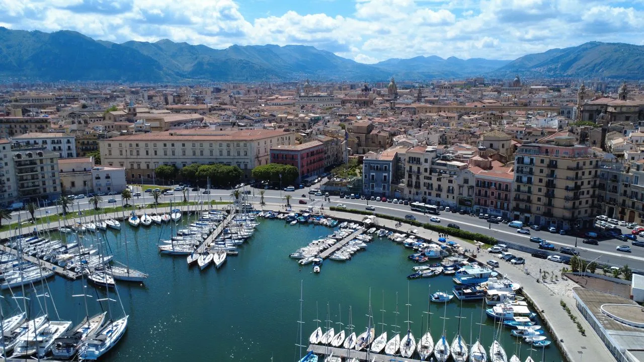 A scenic aerial view of Palermo Marina with surrounding cityscape and mountains in the background.