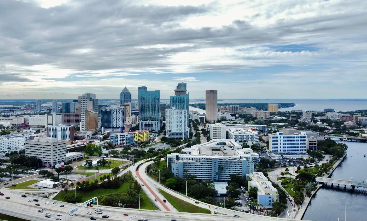 A stunning aerial view of Tampa, FL cityscape featuring modern skyscrapers against clouded skies.