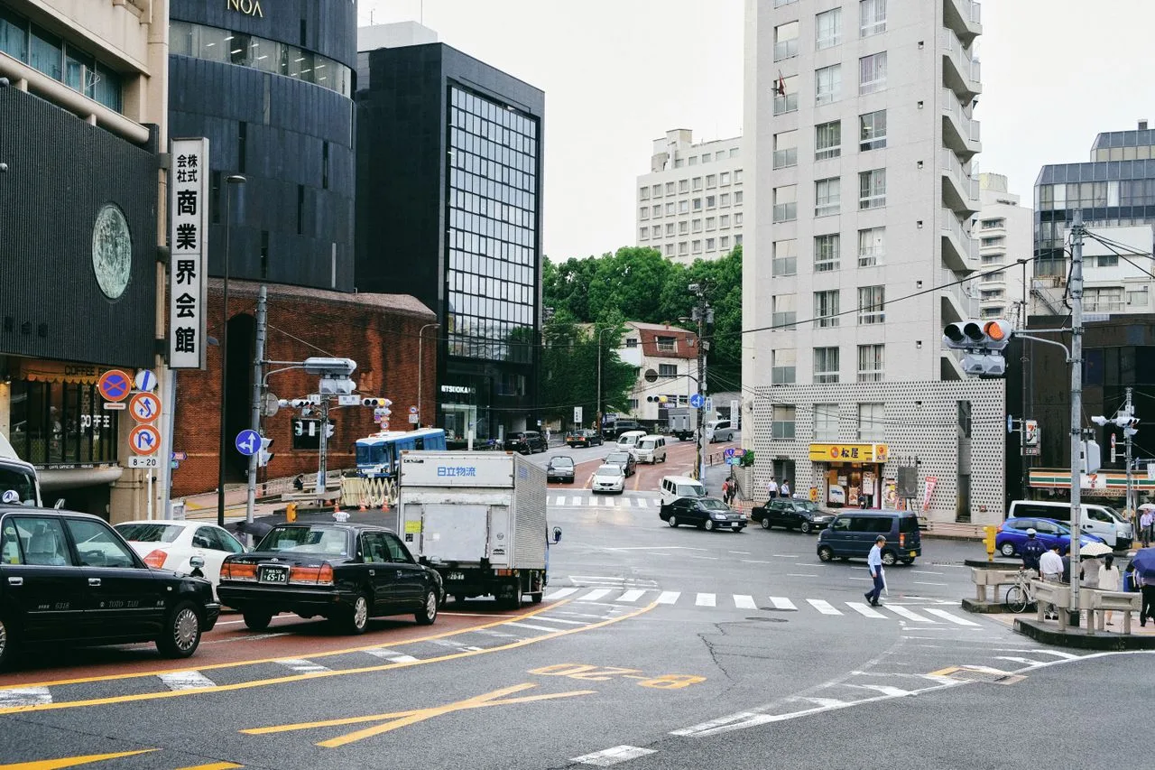 A bustling city street scene at a busy intersection with traffic and pedestrians.