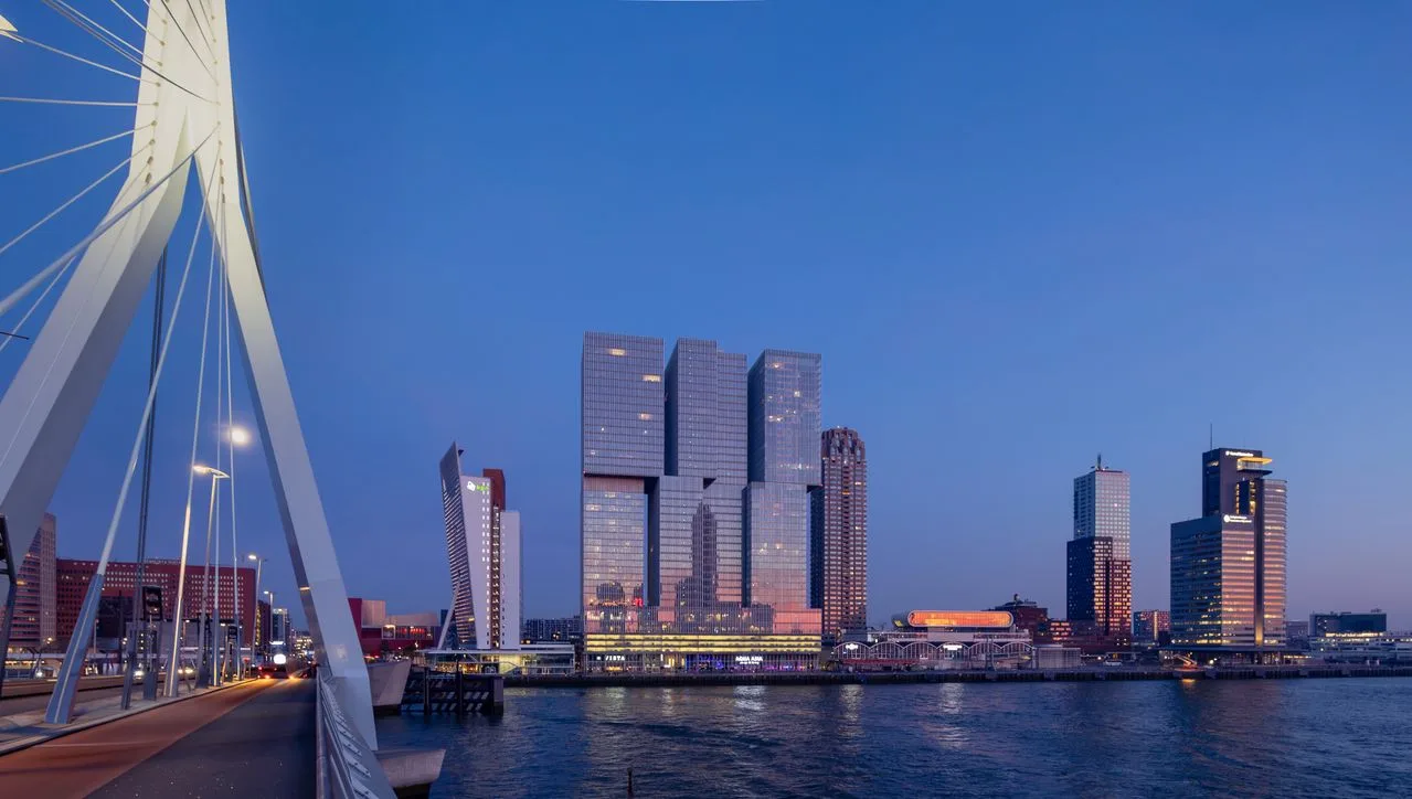 Stunning dusk view of Erasmus Bridge and Rotterdam skyline with modern architecture reflecting in the water.
