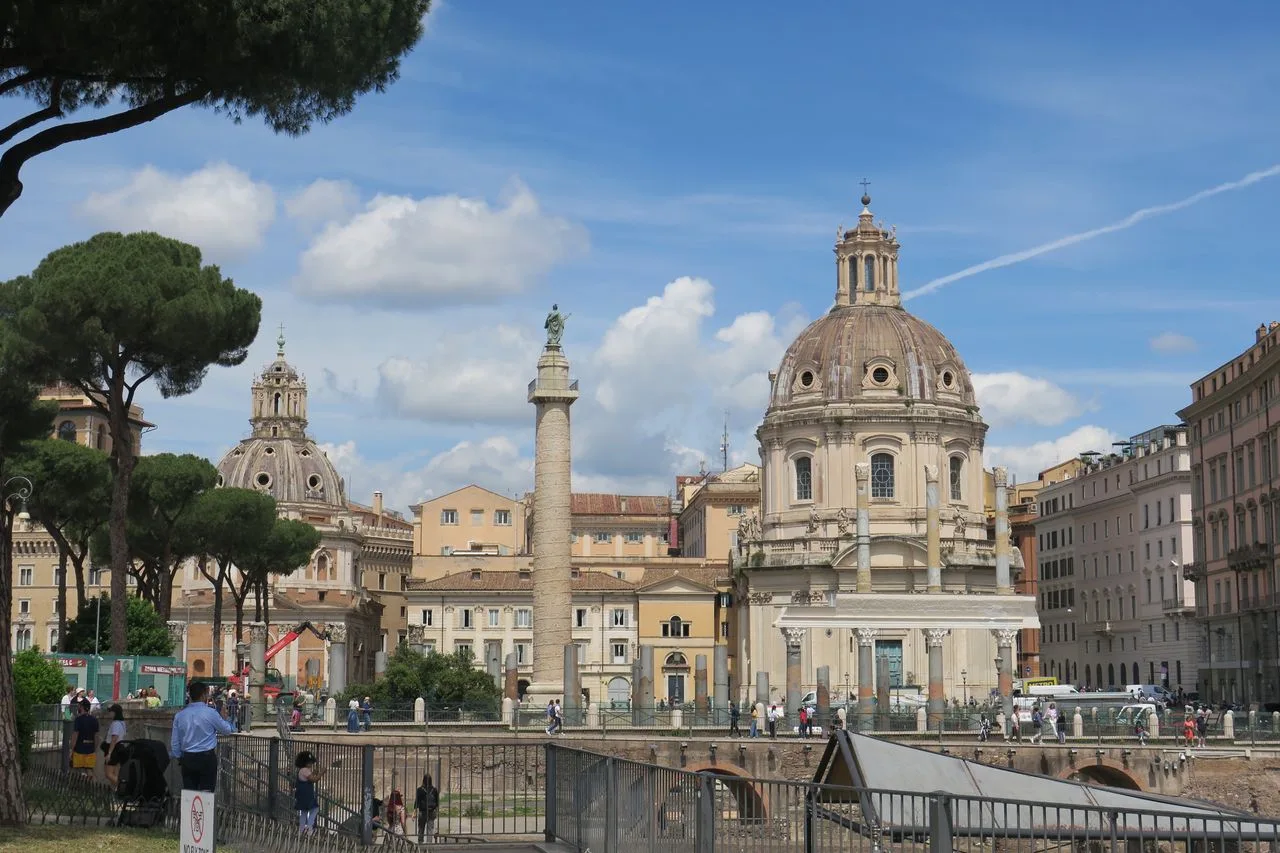 Beautiful view of Rome's historic architecture featuring the iconic Trajan's Column under a bright blue sky.