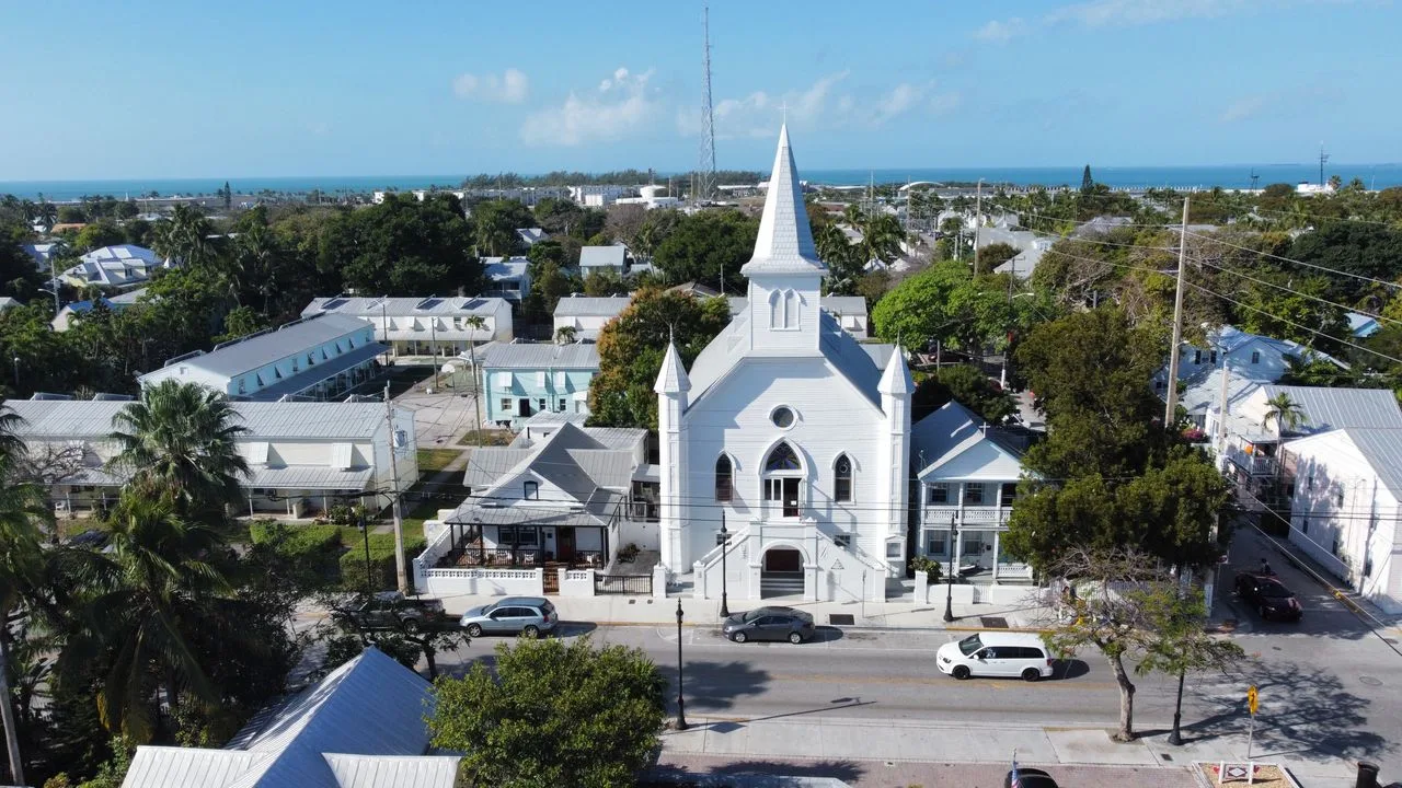 A stunning aerial view of a classic white church in Key West, Florida, with ocean backdrop.