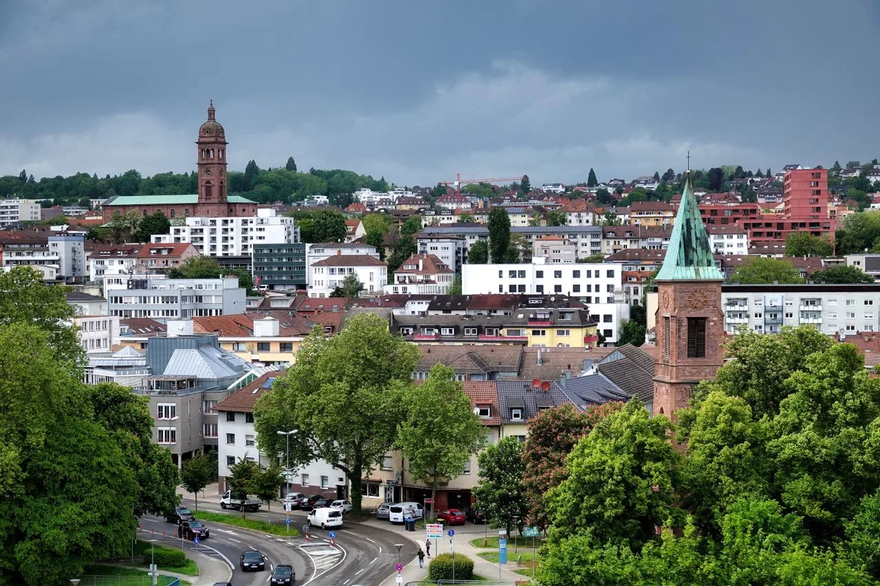 Aerial view of Pforzheim with historical landmarks and lush greenery under cloudy skies.