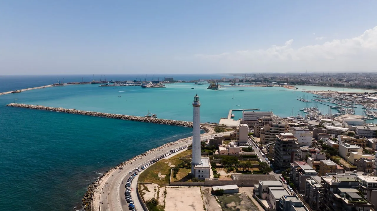 A stunning aerial view of a coastal city with a prominent lighthouse by the turquoise sea.