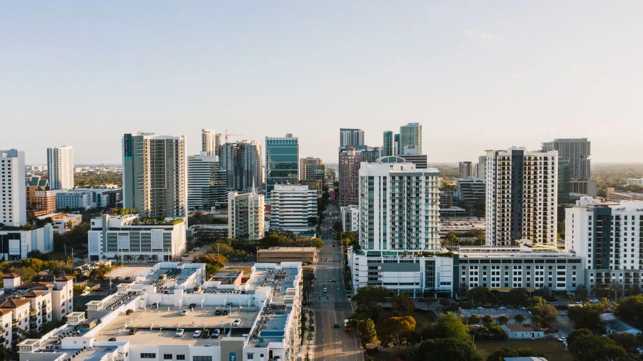 Aerial view of Fort Lauderdale's modern skyline at sunset showcasing urban skyscrapers and city streets.