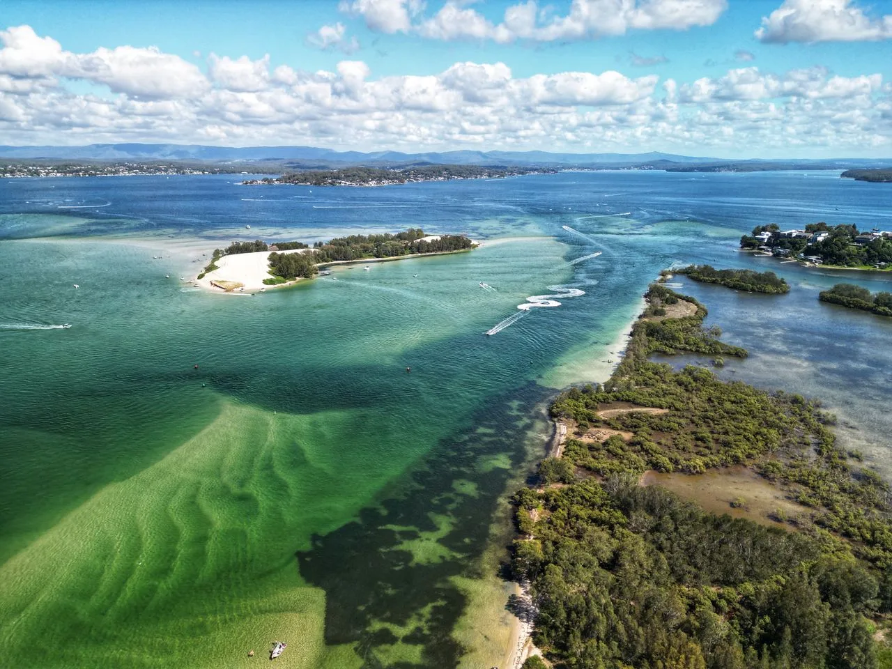 A breathtaking aerial shot of a vibrant coastal waterway with sandy shores and lush greenery.