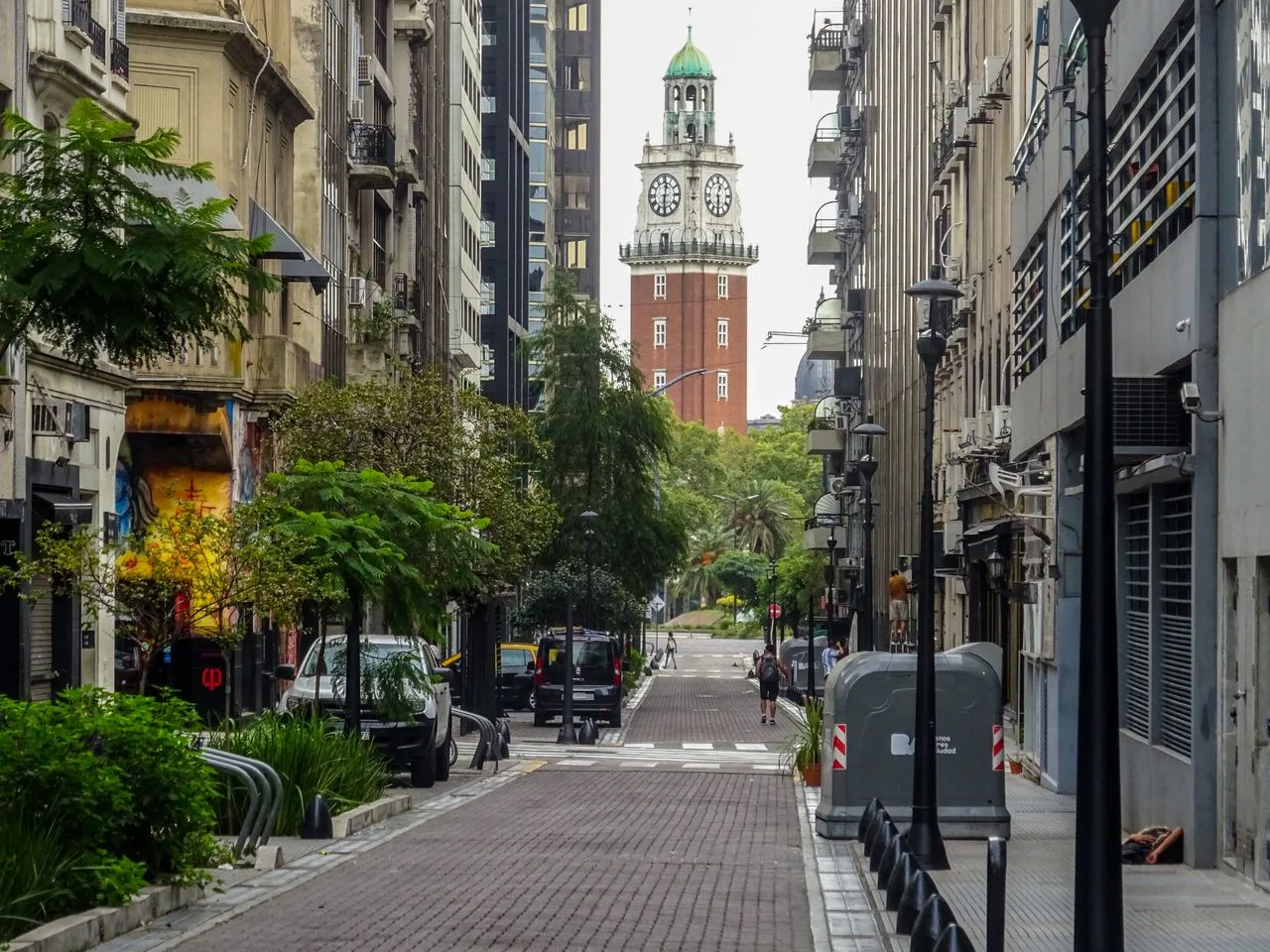 View of a charming street in Buenos Aires with the iconic Torre Monumental clock tower in the distance.