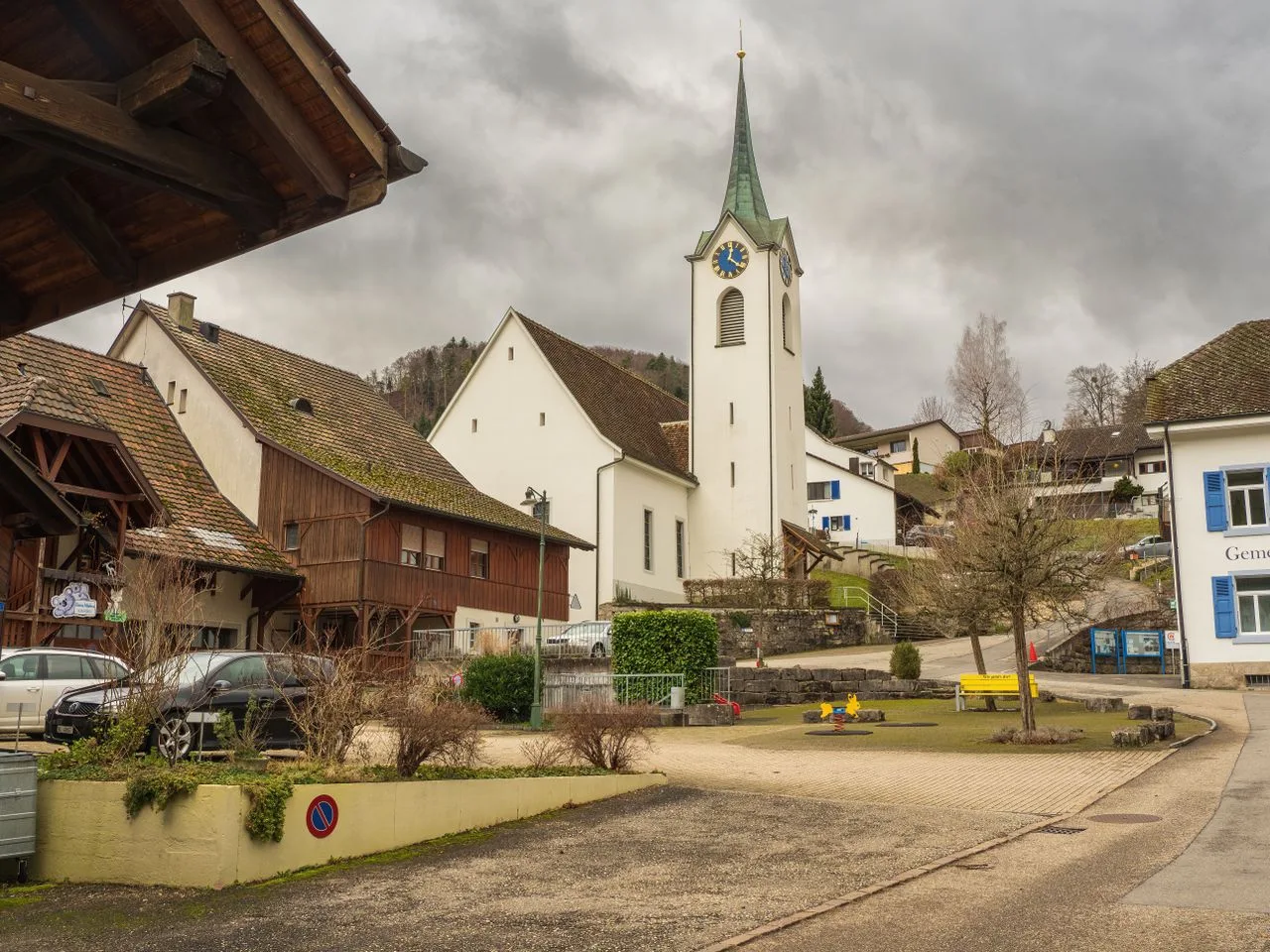 Charming village scene featuring a historic church tower under overcast skies.