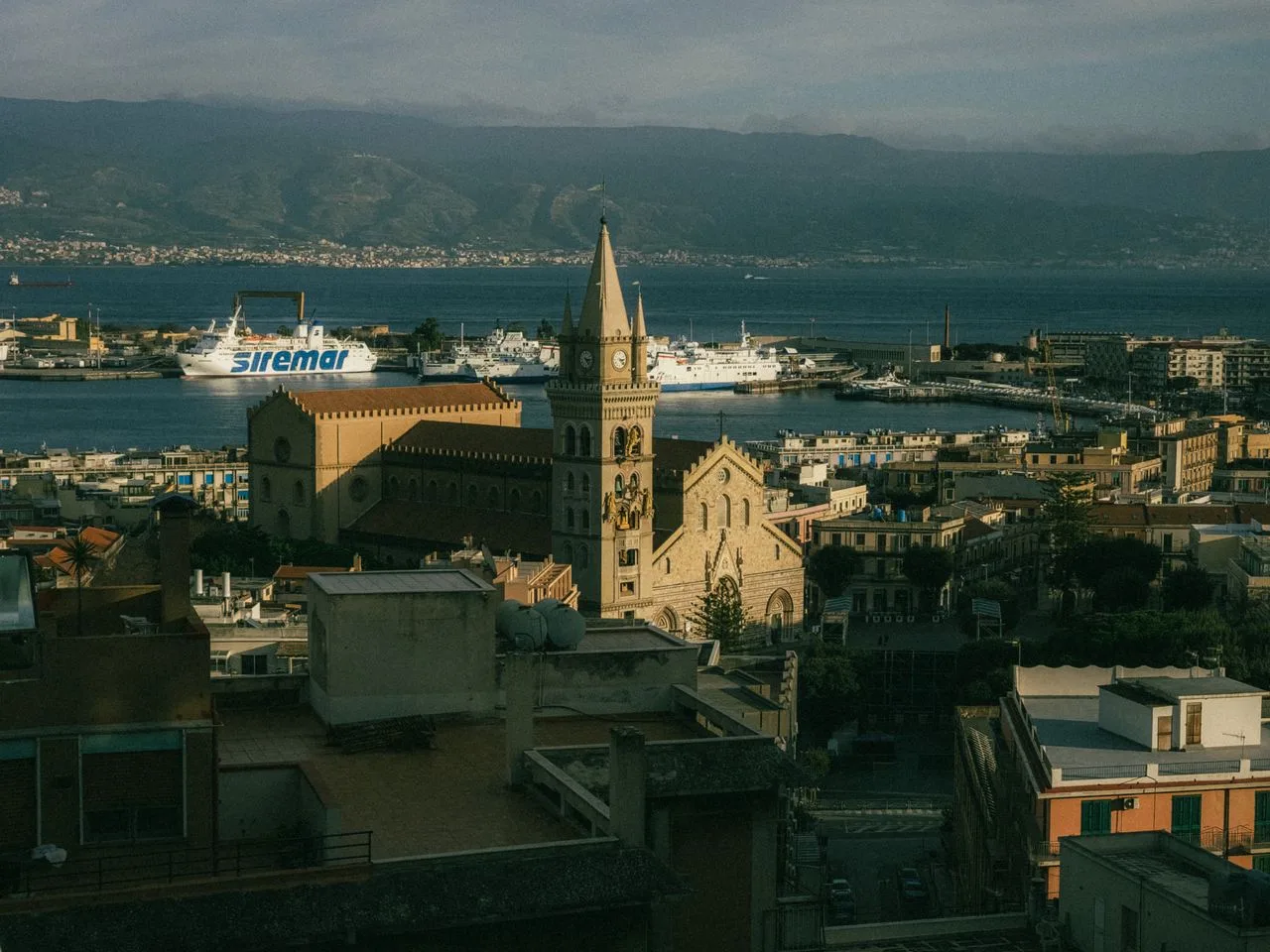 Aerial view of Messina Cathedral with harbor and ferries in the background.