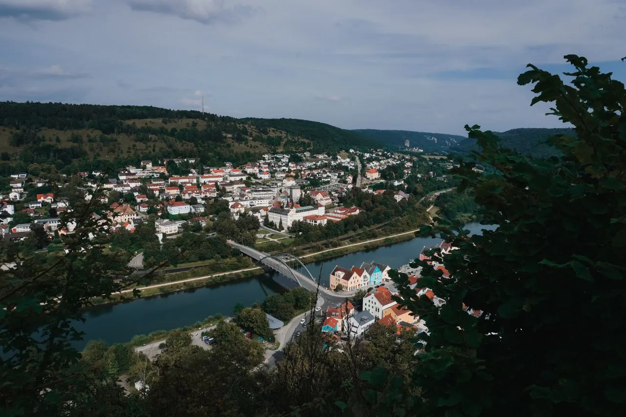 Aerial view of Riedenburg, Germany, showcasing the river, bridges, and lush hills.