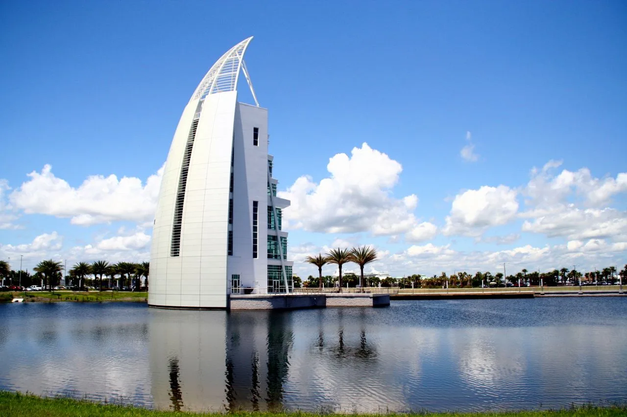 Sleek architectural structure reflecting on water under a bright blue sky in Cape Canaveral, Florida.