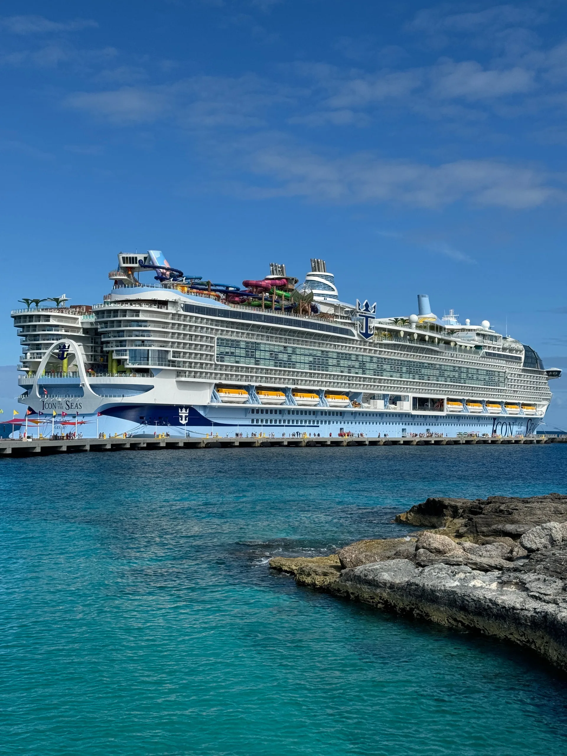 Majestic cruise ship docked at a rocky coastline under clear blue skies.