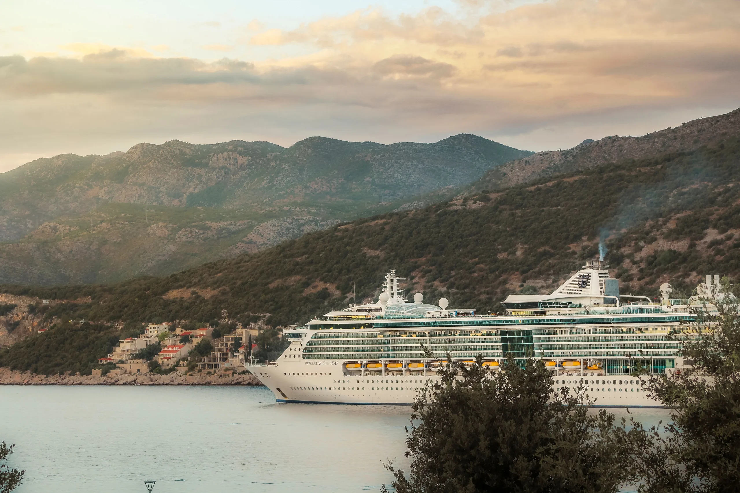 A majestic cruise ship sails along the stunning coastline of Dubrovnik, Croatia at sunset.
