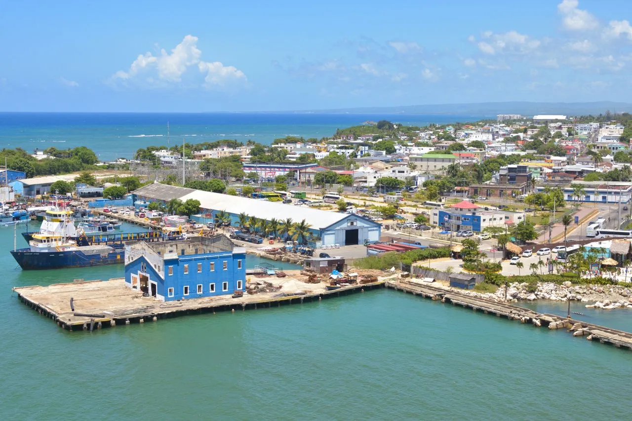Discover Puerto Plata Harbor's vibrant blue buildings and bustling port life.