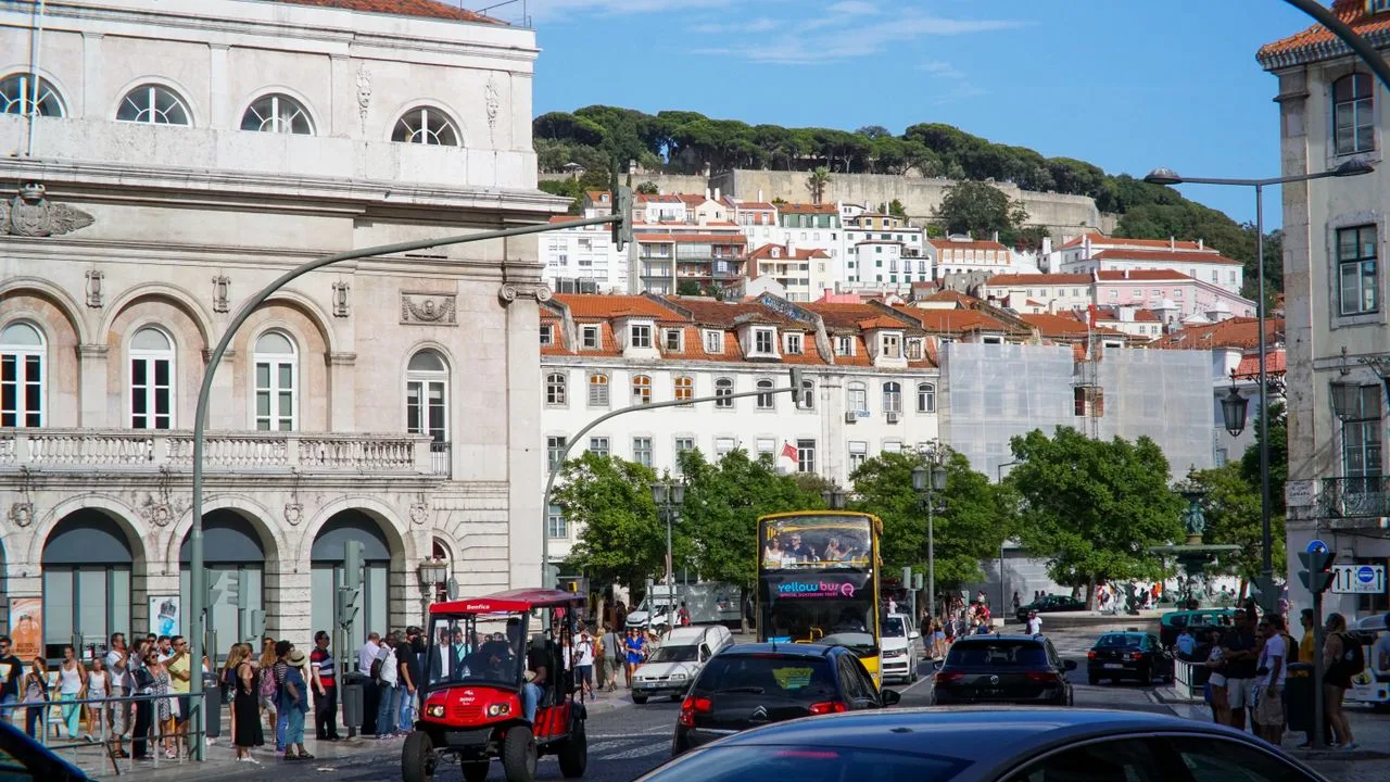 Vibrant daytime view of central Lisbon with iconic architecture and busy street life.